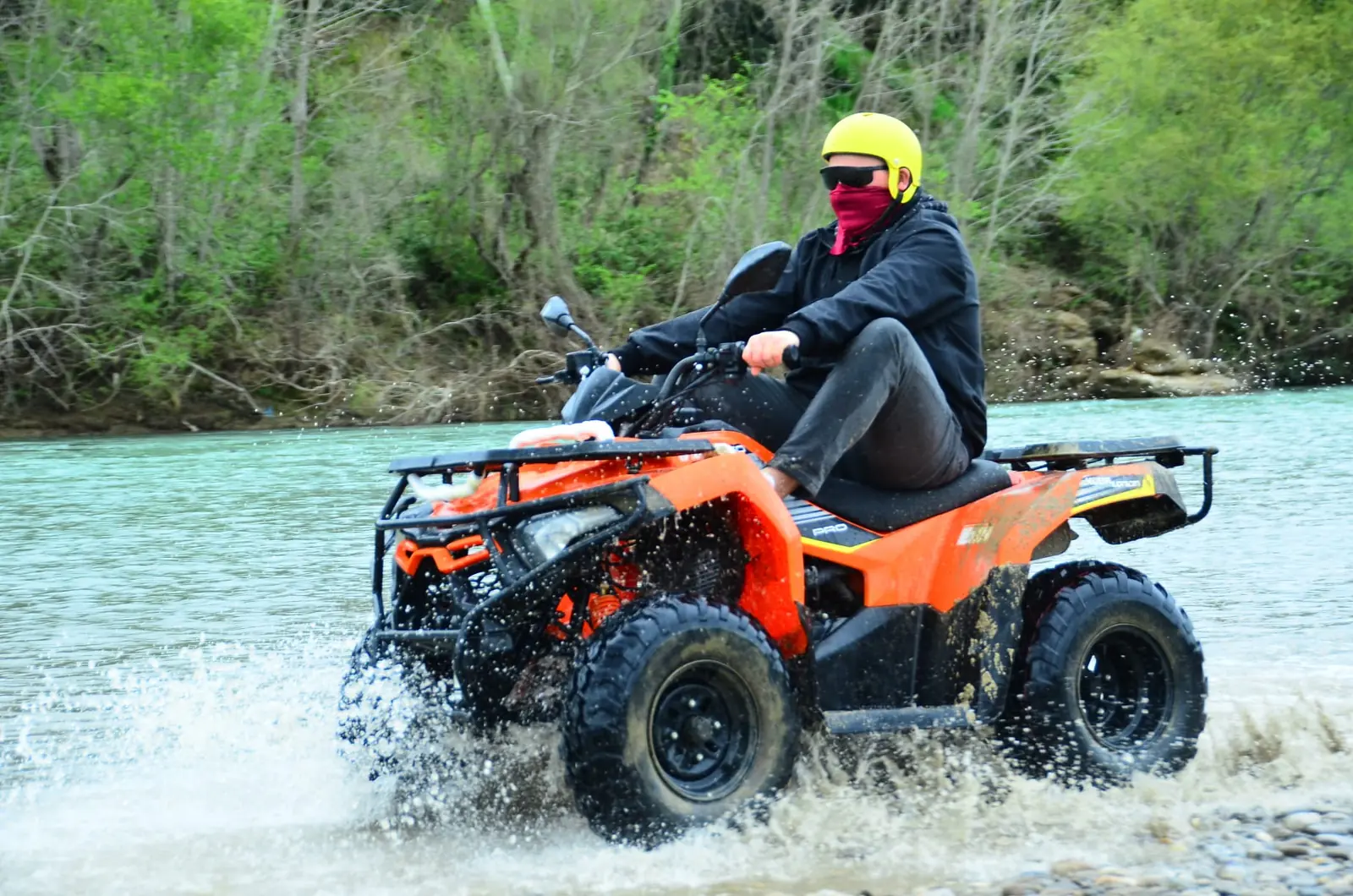 Quad safari rider crossing a shallow river on the off-road route at Aspendos