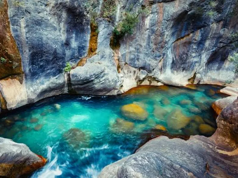 A turquoise natural pool between the rock walls of Sapadere Canyon, seen from above